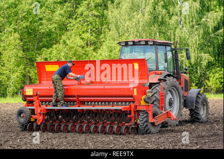 Verhovina, Russia - June 30, 2017: Farmer with tractor seeding - sowing crops at agricultural fields Stock Photo