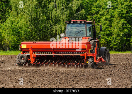 Verhovina, Russia - June 30, 2017: Farmer with tractor seeding - sowing crops at agricultural fields Stock Photo