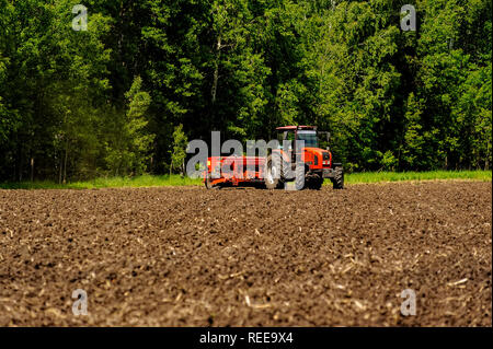 Verhovina, Russia - June 30, 2017: Farmer with tractor seeding - sowing crops at agricultural fields Stock Photo