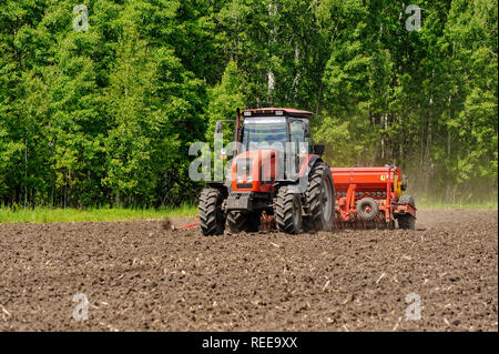 Verhovina, Russia - June 30, 2017: Farmer with tractor seeding - sowing crops at agricultural fields Stock Photo