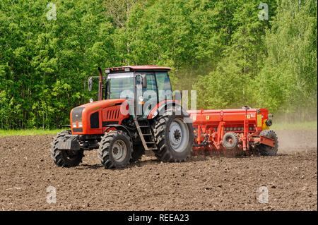 Verhovina, Russia - June 30, 2017: Farmer with tractor seeding - sowing crops at agricultural fields Stock Photo