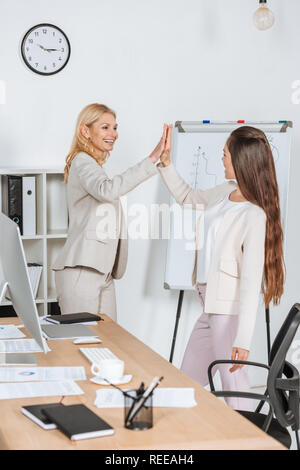 beautiful happy businesswomen smiling and giving high five in office Stock Photo