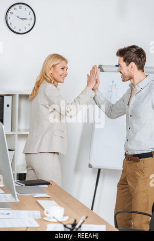 happy businessman and businesswoman smiling and giving high five in office Stock Photo