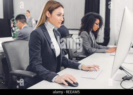 side view of focused young businesswoman using desktop computer at workplace Stock Photo