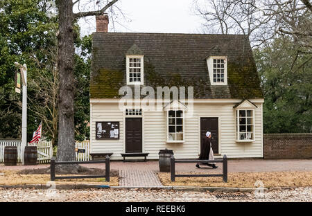 A colonial character walks in front of an 18th century house Stock Photo