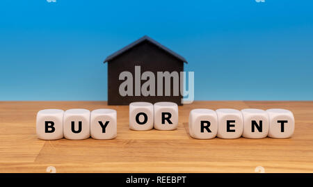 To buy or to rent. Dice form the words 'buy or rent' infront of a model house Stock Photo