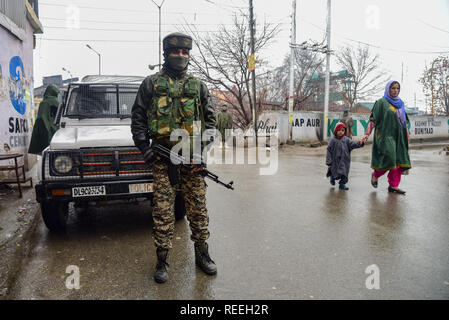 A Kashmiri woman with child seen walking past of Indian army man during restrictions in Srinagar. Kashmiris mark 29th anniversary of Gaw Kadal massacre. More than 50 Kashmiri civilians were killed and more than 250 Peoples were injured when the Indian army opened bullets on the Kashmiri Protestors at Gaw Kadal bridge in Srinagar on 21 January 1990. Authorities imposed restrictions in Gaw Kadal area of Srinagar to prevent Anti Indian protests against the Killings. Stock Photo