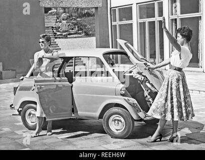 Driving in the 1950s. Two young women is standing beside a car model BMW 600. A micro car model with the front door really in front. 1958 Stock Photo