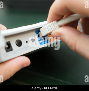 Man plugging internet cable into wifi router. Stock Photo