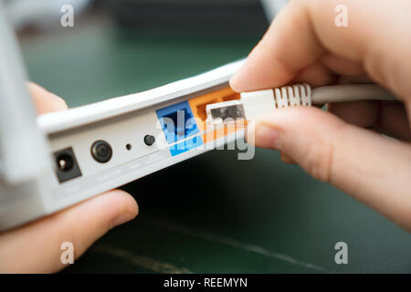 Man plugging internet cable into wifi router. Stock Photo