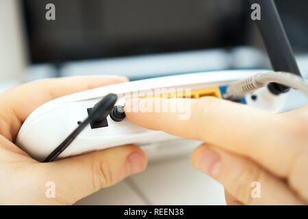 Man pressing power button on the wifi router. Stock Photo