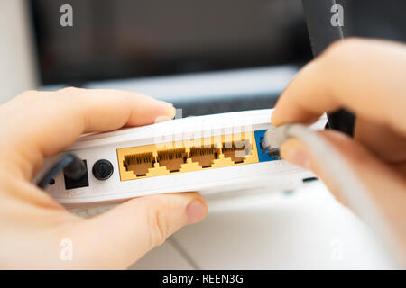 Man plugging internet cable into wifi router. Stock Photo