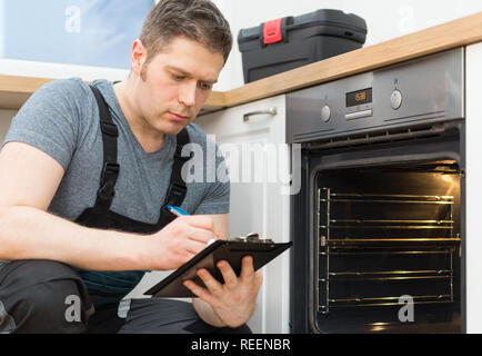 Handyman doing inspection of domestic oven in the kitchen. Stock Photo