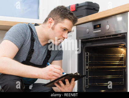 Handyman doing inspection of domestic oven in the kitchen. Stock Photo
