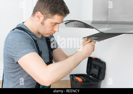 Handsome foreman fixing exhaust hood in the kitchen. Stock Photo