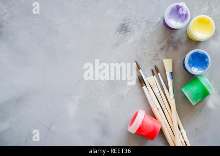 Drawing tools, set of clean paint brushes and multicolor paints on gray background. Paint brushes of different sizes. Copy space, top view Stock Photo