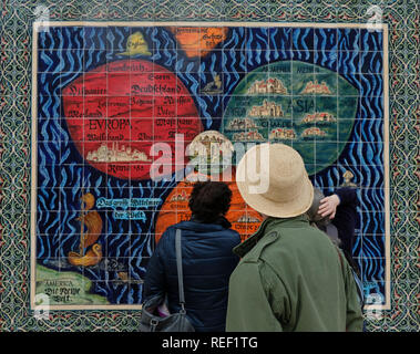 Tourist looking at a mosaic model by Armenian ceramicist Arman Darian depicting the Bunting Clover Leaf Map, also known as The World in a Cloverleaf, an historic mappa mundi drawn by the German Protestant pastor, Heinrich Bünting. in which Jerusalem is in the centre of the map surrounded by the three continents, comprising three leaves of a clover shape installed on the fence of Safra Square at the site of Jerusalem's city hall. Israel Stock Photo