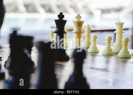 Black and white chess kings faced between defocused pieces on wooden board. Stock Photo