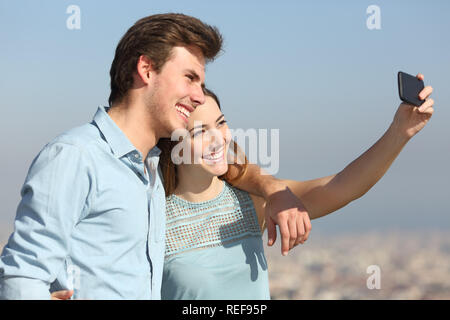 Happy couple taking selfies with smart phone in a city outskirts Stock Photo