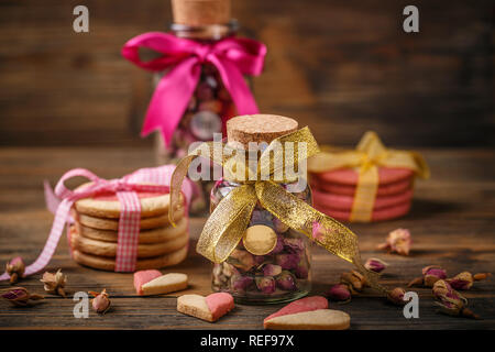 Valentine's day and mother's day concept, rose buds tea in glass jar and biscuits on wooden background Stock Photo