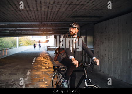 Hipster businessman commuter with electric bicycle traveling to work in city. Stock Photo