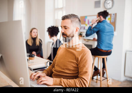 Group of young businesspeople with computer working in a modern office. Stock Photo
