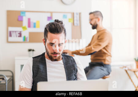 Two young male businesspeople with computer working in a modern office. Stock Photo