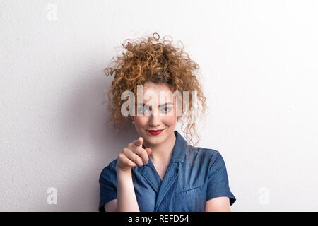 Young beautiful happy woman in studio, pointing at you. Stock Photo