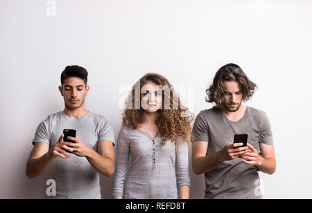A young woman with two friends occupied with modern technology. Stock Photo