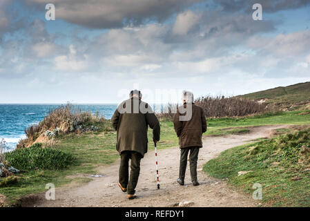 A mature couple walking along the South West Coast Path on the Headland in Newquay Cornwall; Stock Photo