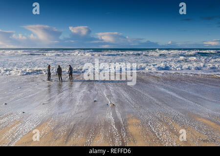 People in wetsuits standing on the shoreline at Fistral Beach in Newquay Cornwall. Stock Photo