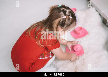 Little girl playing toy baby dishes at home Stock Photo