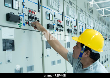 Electrical technician checking electrical control board of motor starting system in switch gear room, maintenance and service. - Image Stock Photo