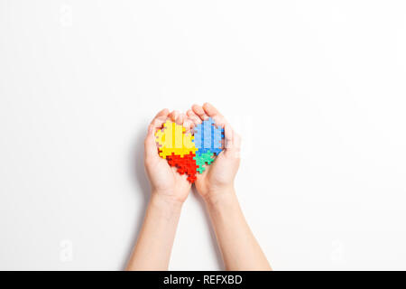 Child hands holding colorful heart on white background. World autism awareness day concept Stock Photo