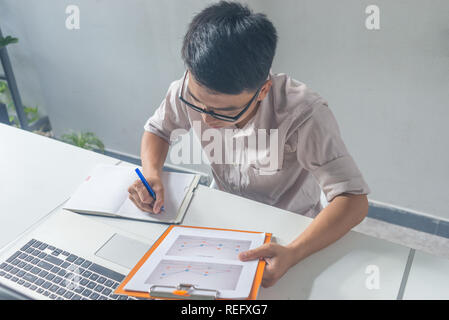 Young Asian businessman writing in a notebook Stock Photo