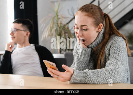 SMS. Closeup portrait funny shocked anxious scared young girl looking at phone seeing bad news photos message with disgusting emotion on face. Human reaction, expression Stock Photo