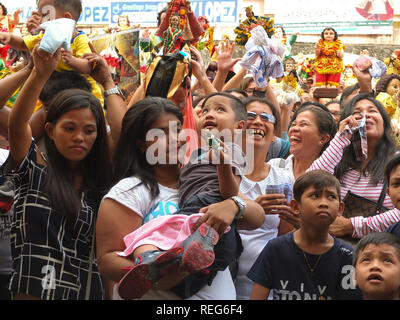 A young boy with a miniature replica of a Sto. Niño in his hand, along with his mother with so much jubilation could be seen in their eyes during the Blessing of the Sto. Niños in Tondo. Catholic Devotees bring their Sto. Niños to be blessed by holy water by the parish priest of Tondo church to celebrate the Feast of the Santo Niño (Child Jesus). Stock Photo