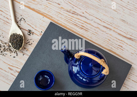 Overhead view of oriental teapot and cup, with green tea leaves. Stock Photo