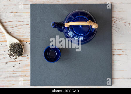 Overhead view of oriental teapot and cup, with green tea leaves. Stock Photo
