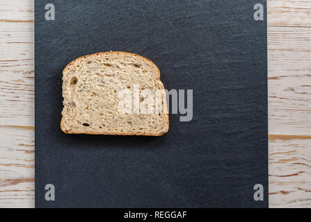 Slice of seeded batch bread on a piece of slate. Stock Photo