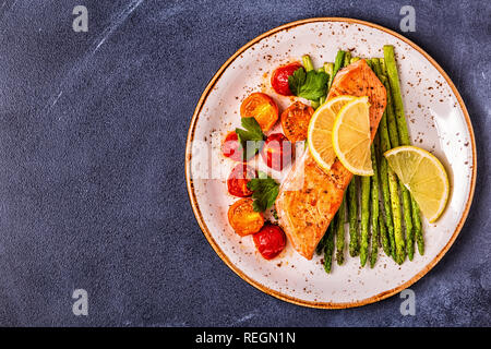 Grilled salmon with asparagus and tomatoes, top view. Stock Photo