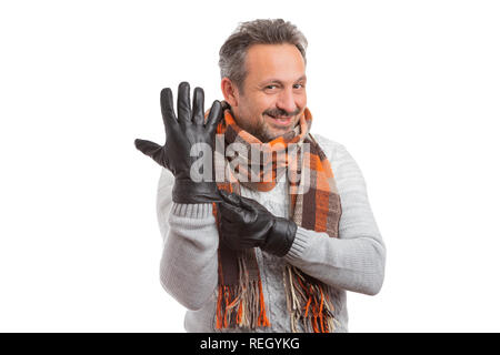 Friendly man showing black leather glove as adjusting it with other hand wearing scarf and knitted pullover as winter fashion concept isolated on whit Stock Photo