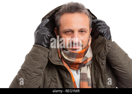 Man getting ready for winter weather with hood of jacket wearing brown and orange scarf isolated on white background Stock Photo