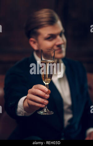 Very handsome man in a suit raises the glass of champagne Stock Photo