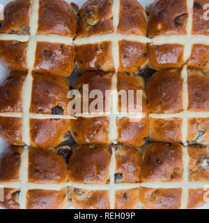 Looking down from above onto a seasonal food background of sticky and sweet Easter hot cross buns in a batch bake and square frame with copy space Stock Photo