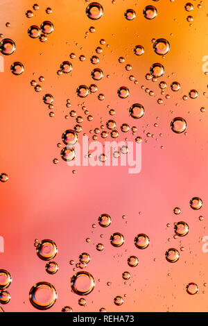 Macro shot of backlit liquid with small bubbles in it over colored background. Stock Photo