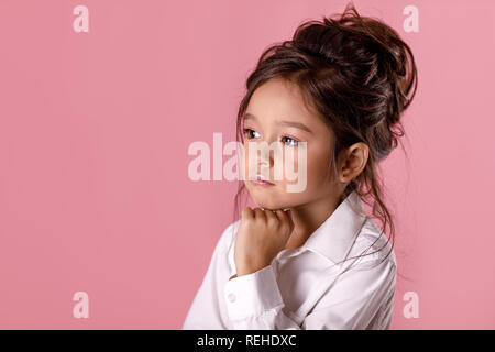 beautiful doubtful, thoughtful little girl in white shirt with hairstyle Stock Photo