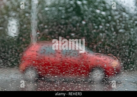 A red car seen through a wet car window covered with raindrops. Stock Photo