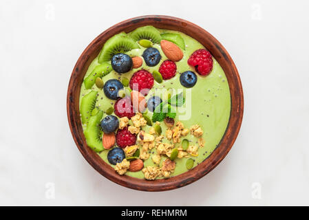matcha tea green smoothie bowl with fresh berries, nuts, seeds and homemade granola for healthy vegan vegetarian diet breakfast. top view. flat lay Stock Photo