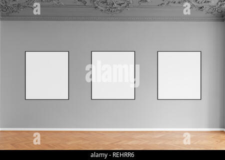 three empty picture frames hanging on grey wall in gallery Stock Photo